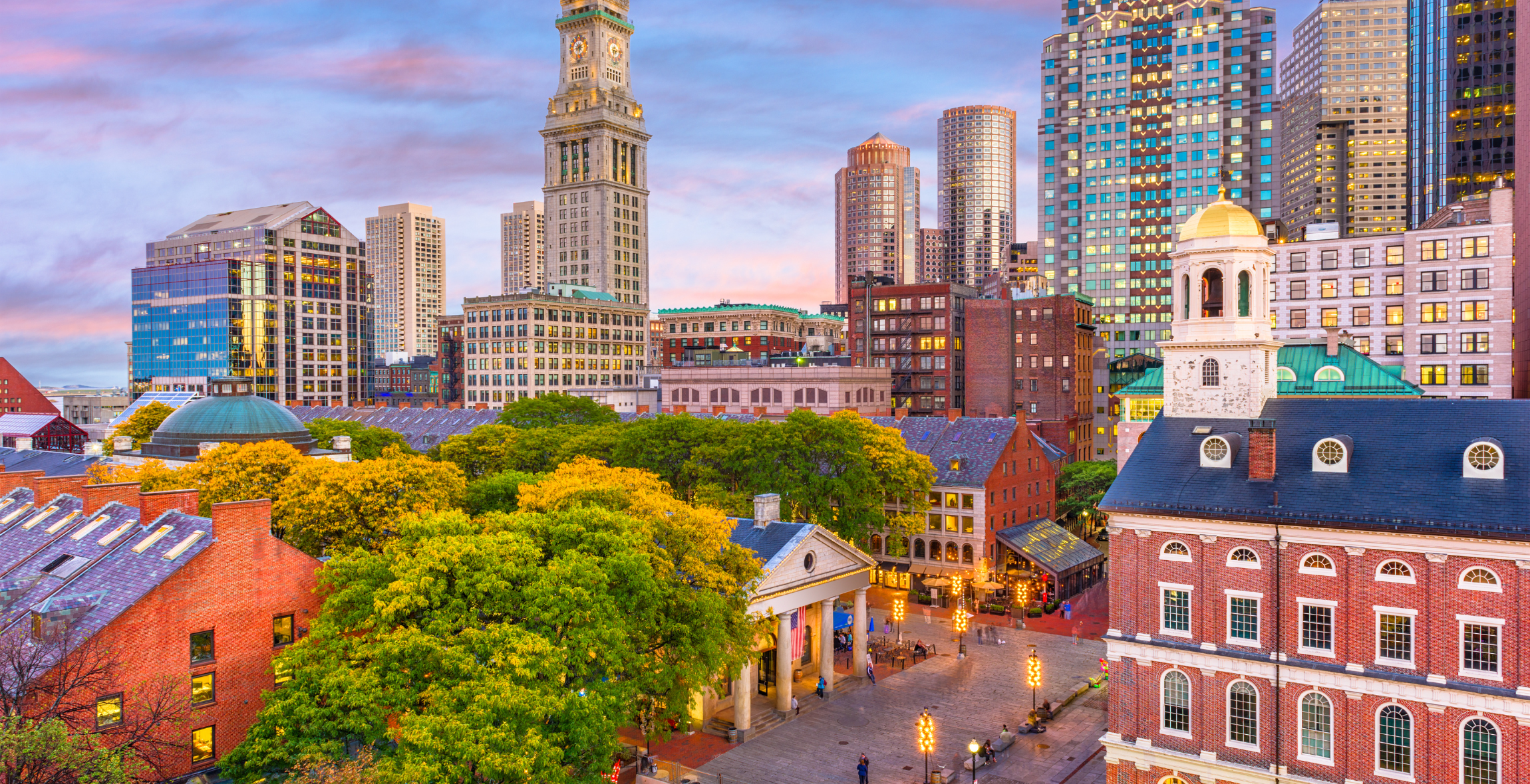 buildings lit up in the evening with trees in between, in Boston, MA.