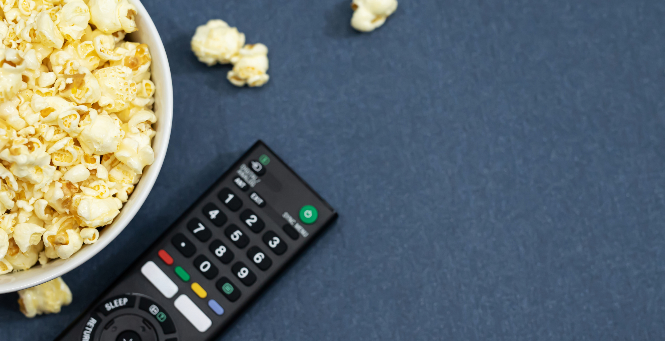 popcorn spills over next to a television remote controller