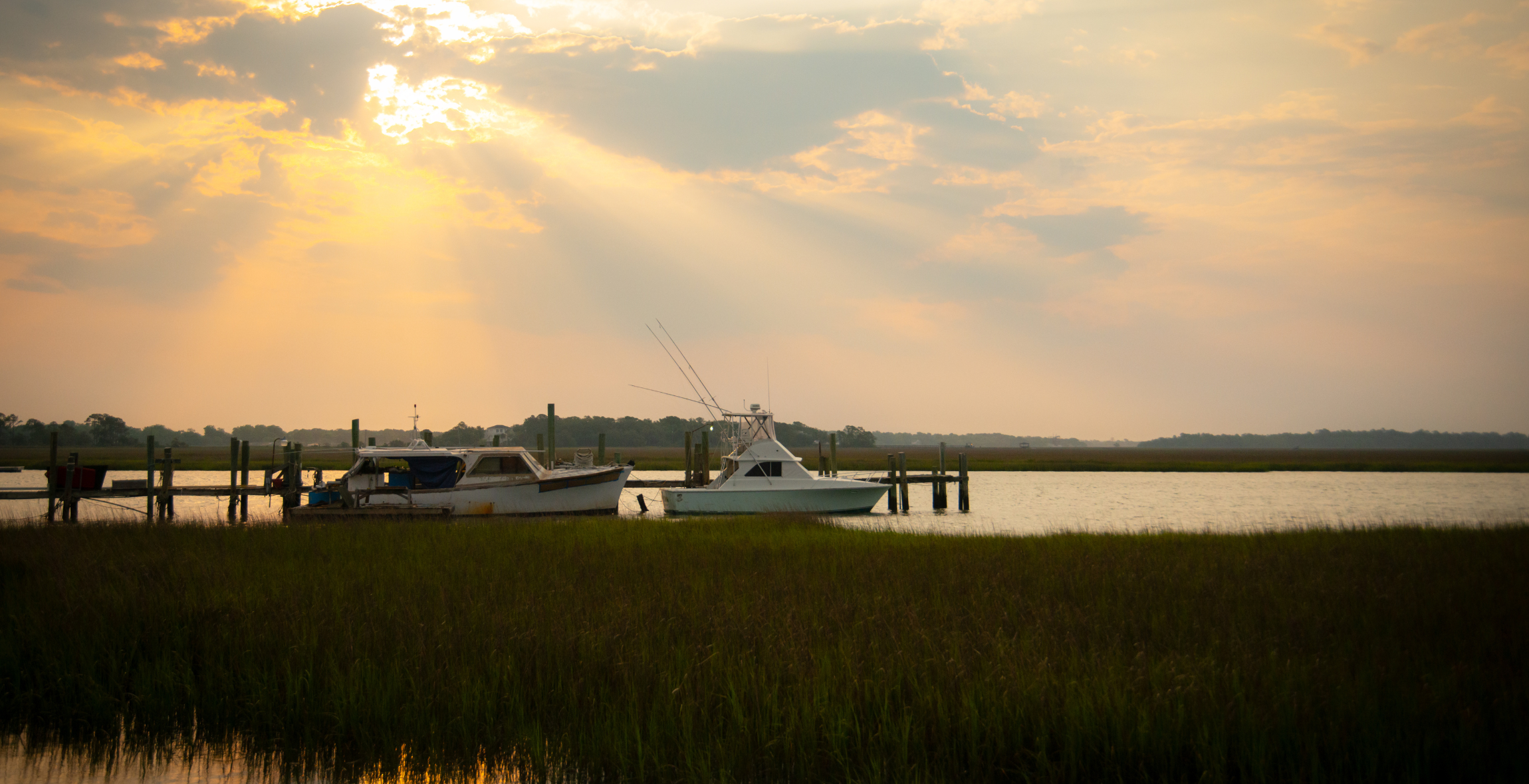 two boats sit in marshy water near a dock in John's Island, South Carolina